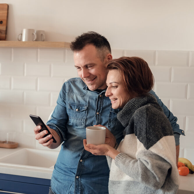 Happy,Couple,Reading,News,On,Mobile,Phone,And,Having,Breakfast